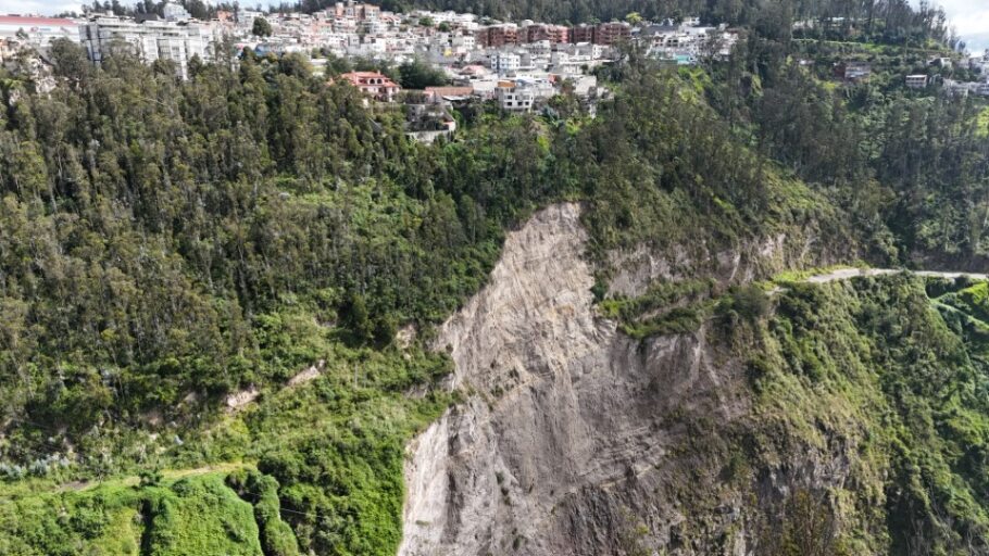 Quebrada urbana de Quito con talud, vegetación y barrio en el borde